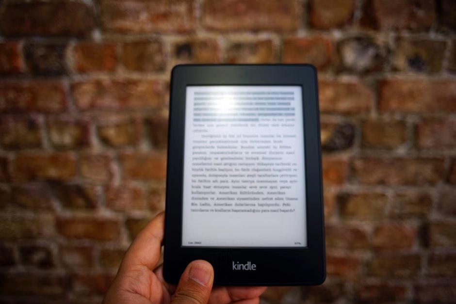 A hand holding an e-reader displaying a page of text