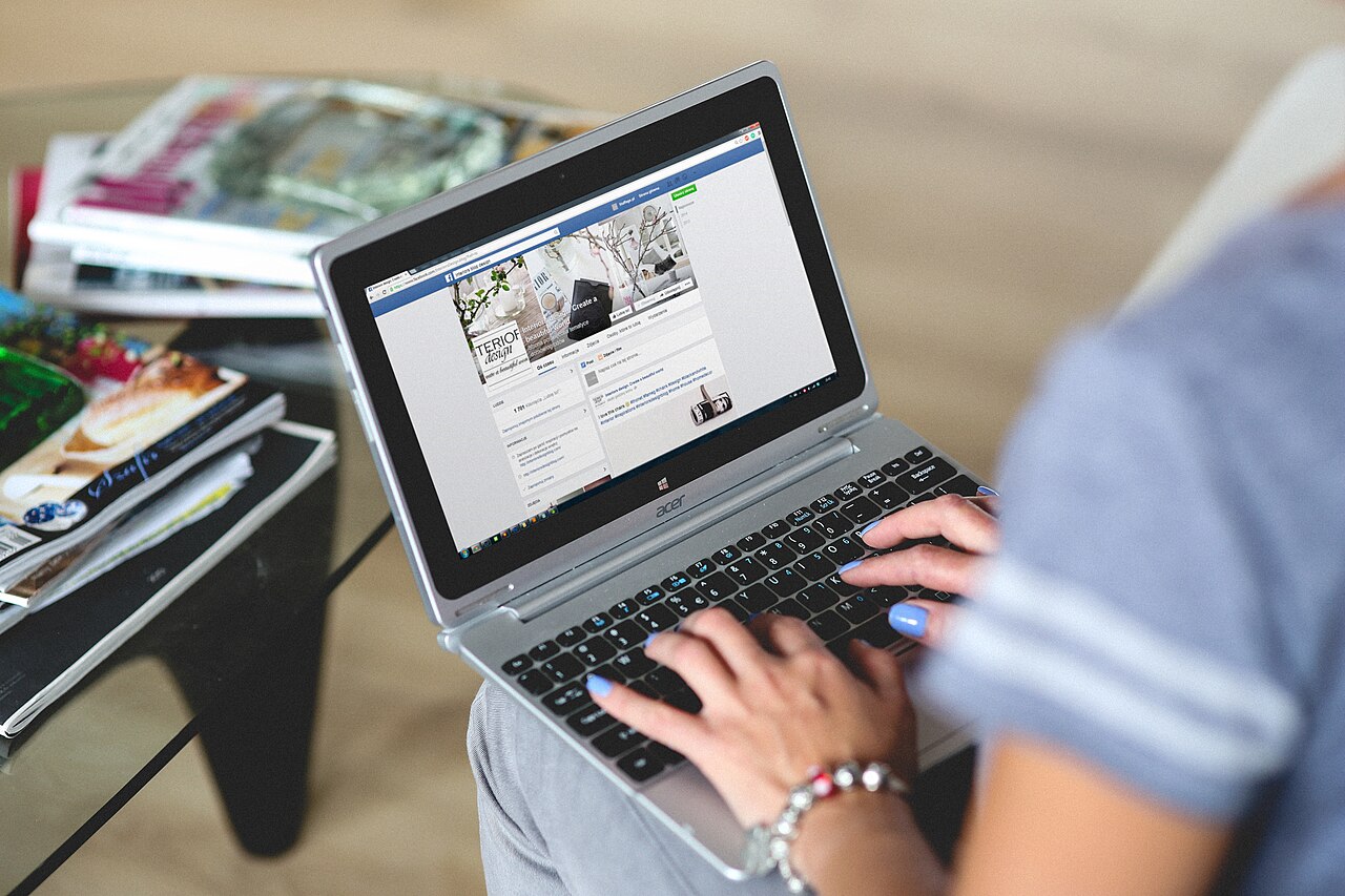 Hands using a laptop keyboard to browse a website.